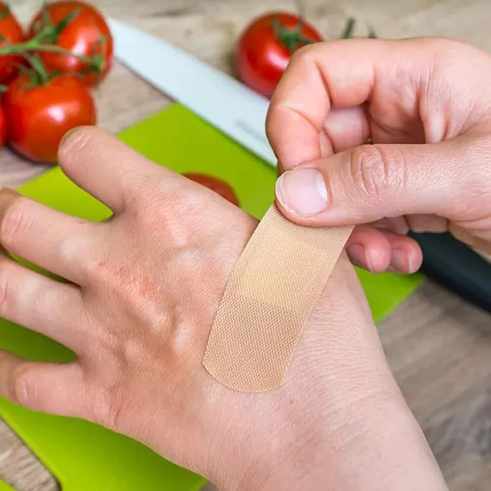A plaster going onto a hand at a kitchen cutting board