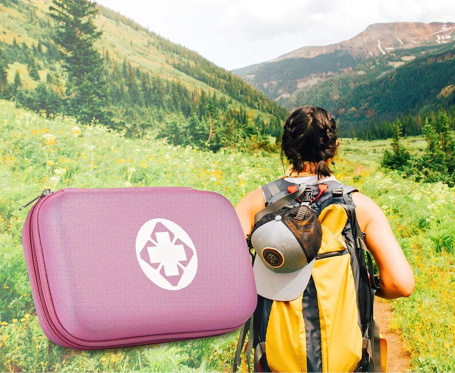 A hiker on a mountain meadow with a pink AMORNING first aid kit