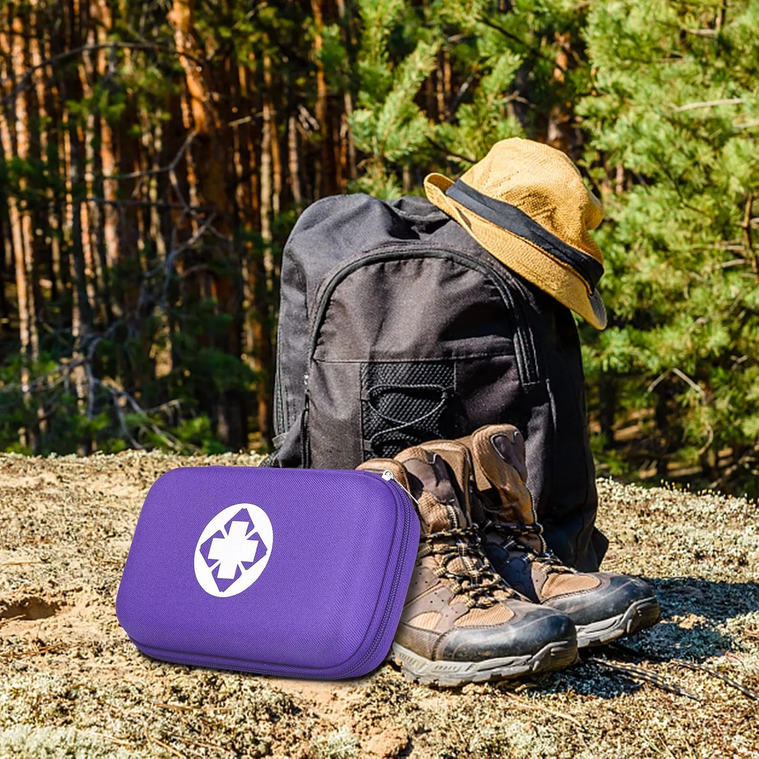 A purple AMORNING first aid kit by a backpack, a hat and boots in a pine forest